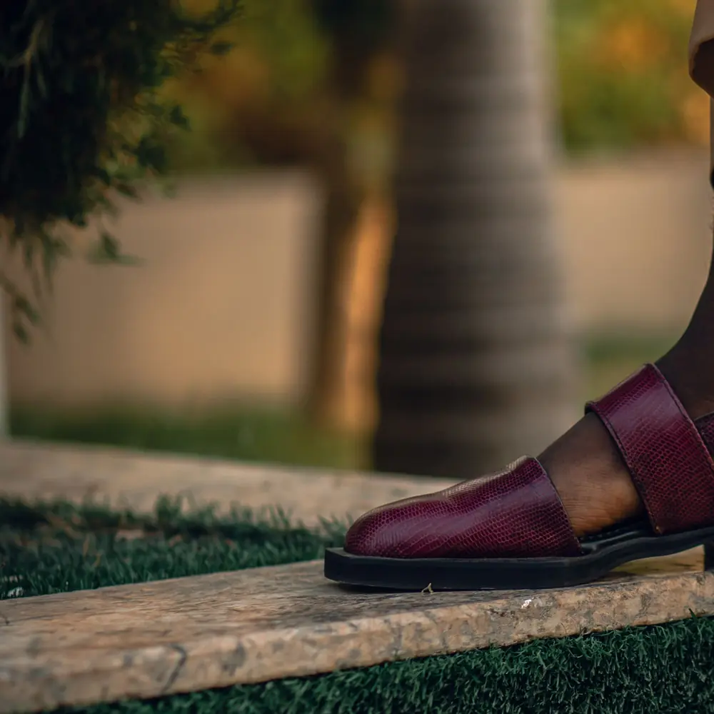 Maroon Peshawari chappal on a garden step