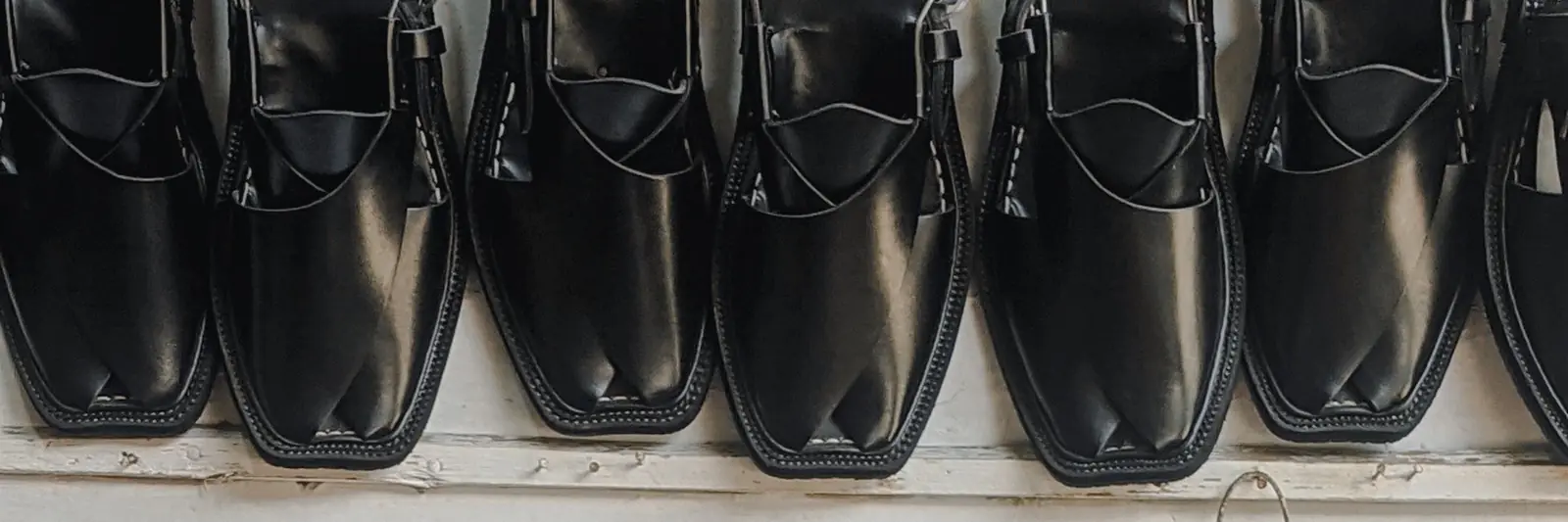 Finished black Peshawari chappals hanging in a row